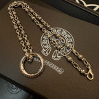 Silver charm necklace with circular ring pendant and long chain strand on box.