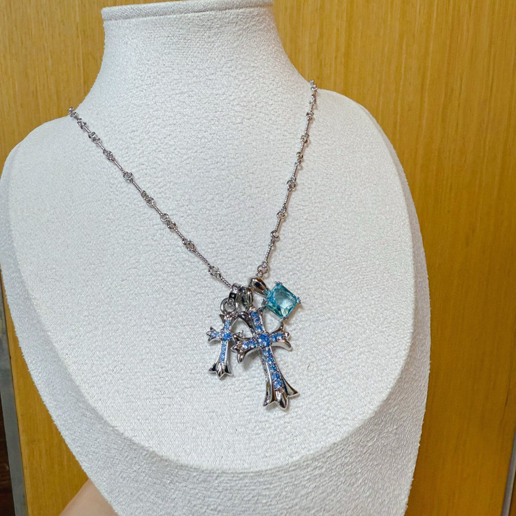 Silver cross pendant necklace with blue gemstone accents on a chain
