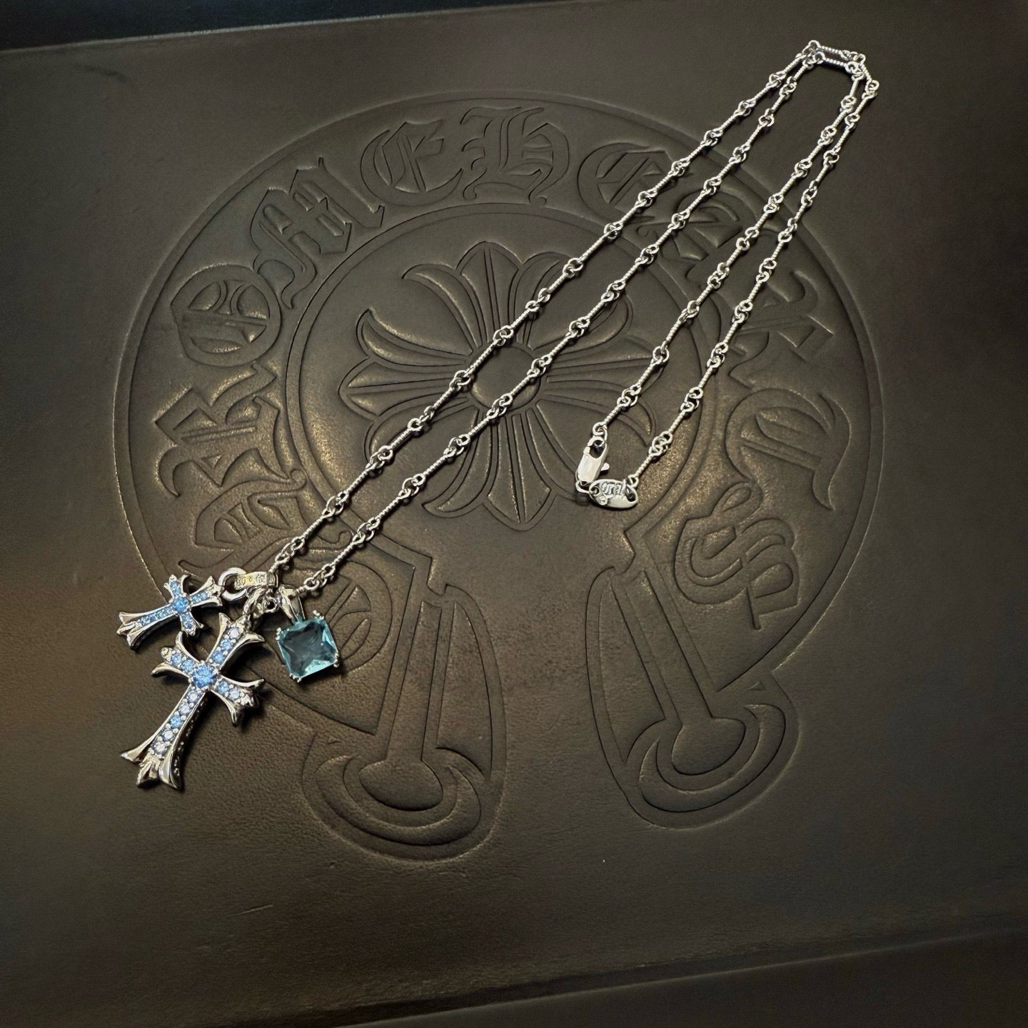 Silver cross pendant necklace with blue gemstones and long layered chain