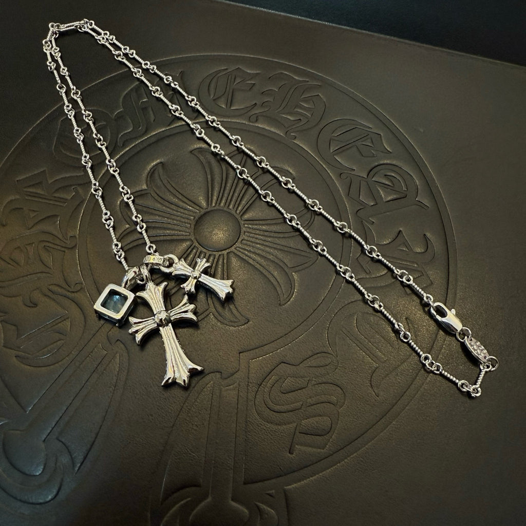 Silver cross pendant necklace with blue gemstone accents on a chain