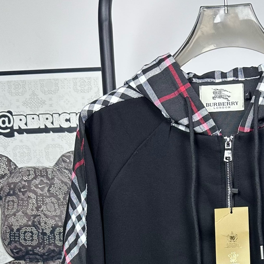 Dark navy zip jacket with plaid hood trim and a visible front zipper pull