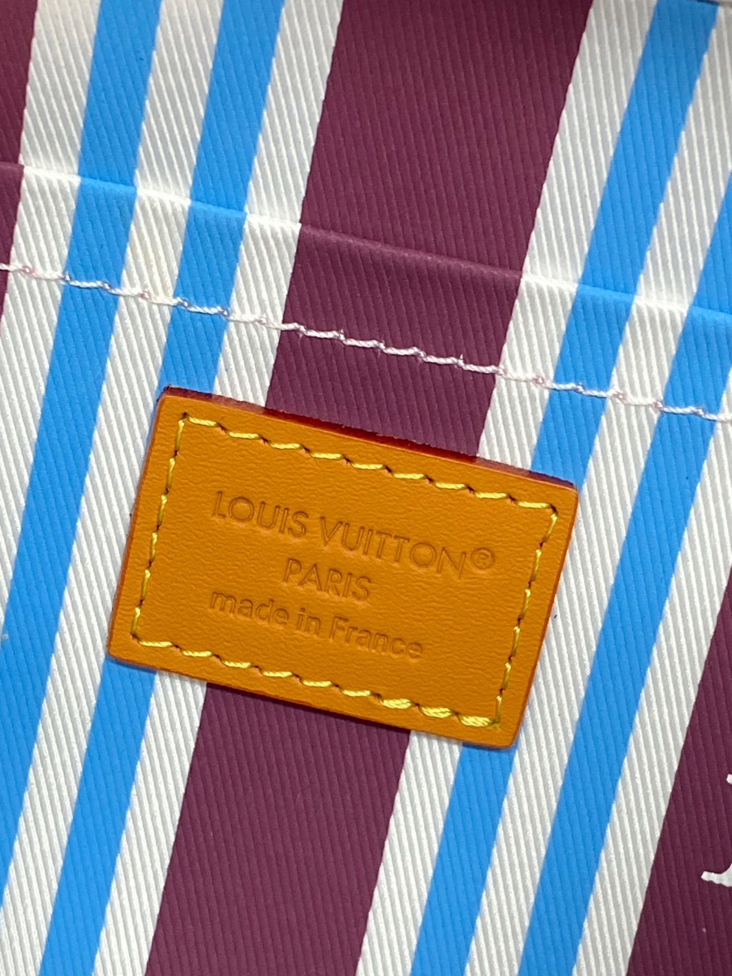 Louis Vuitton crossbody bag interior label on blue-and-white striped lining