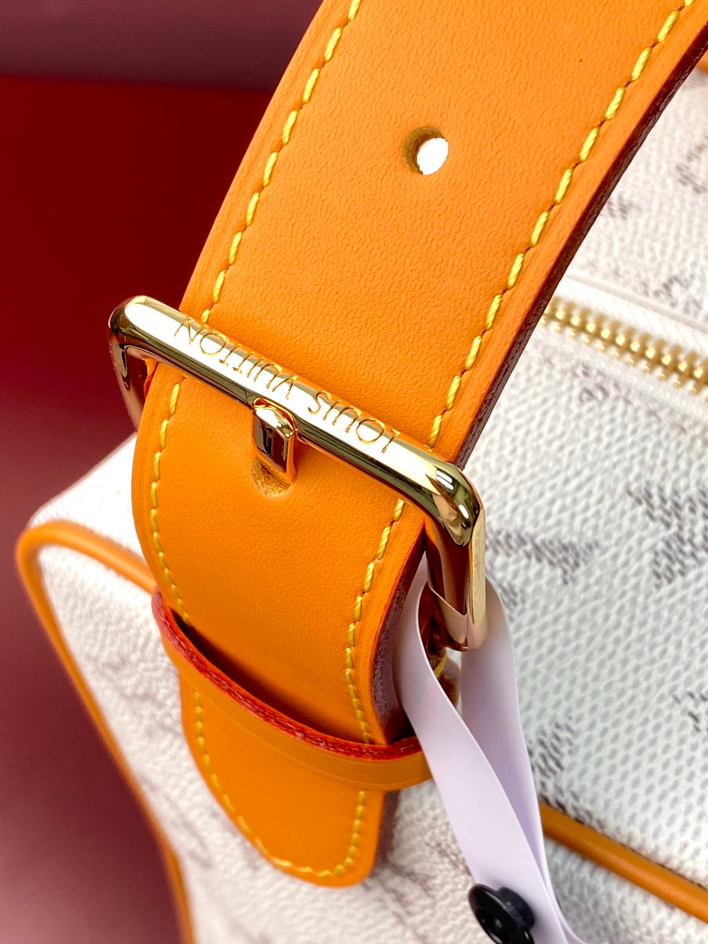 Louis Vuitton crossbody bag hardware detail on tan leather strap with gold clasp