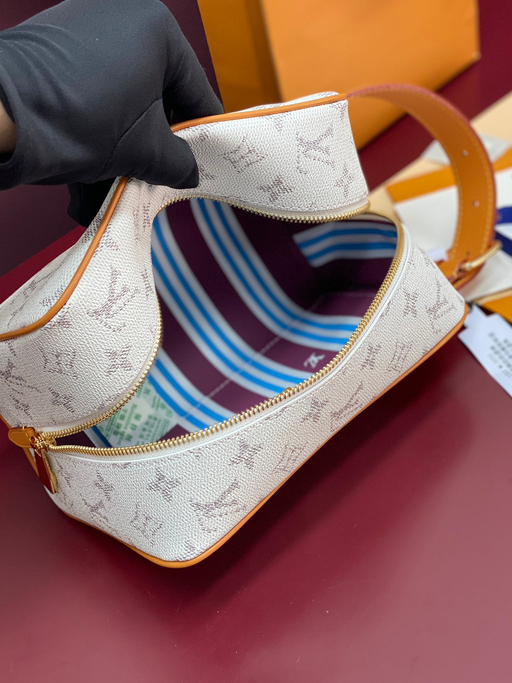 Louis Vuitton crossbody bag open view showing blue striped fabric lining and gold zipper