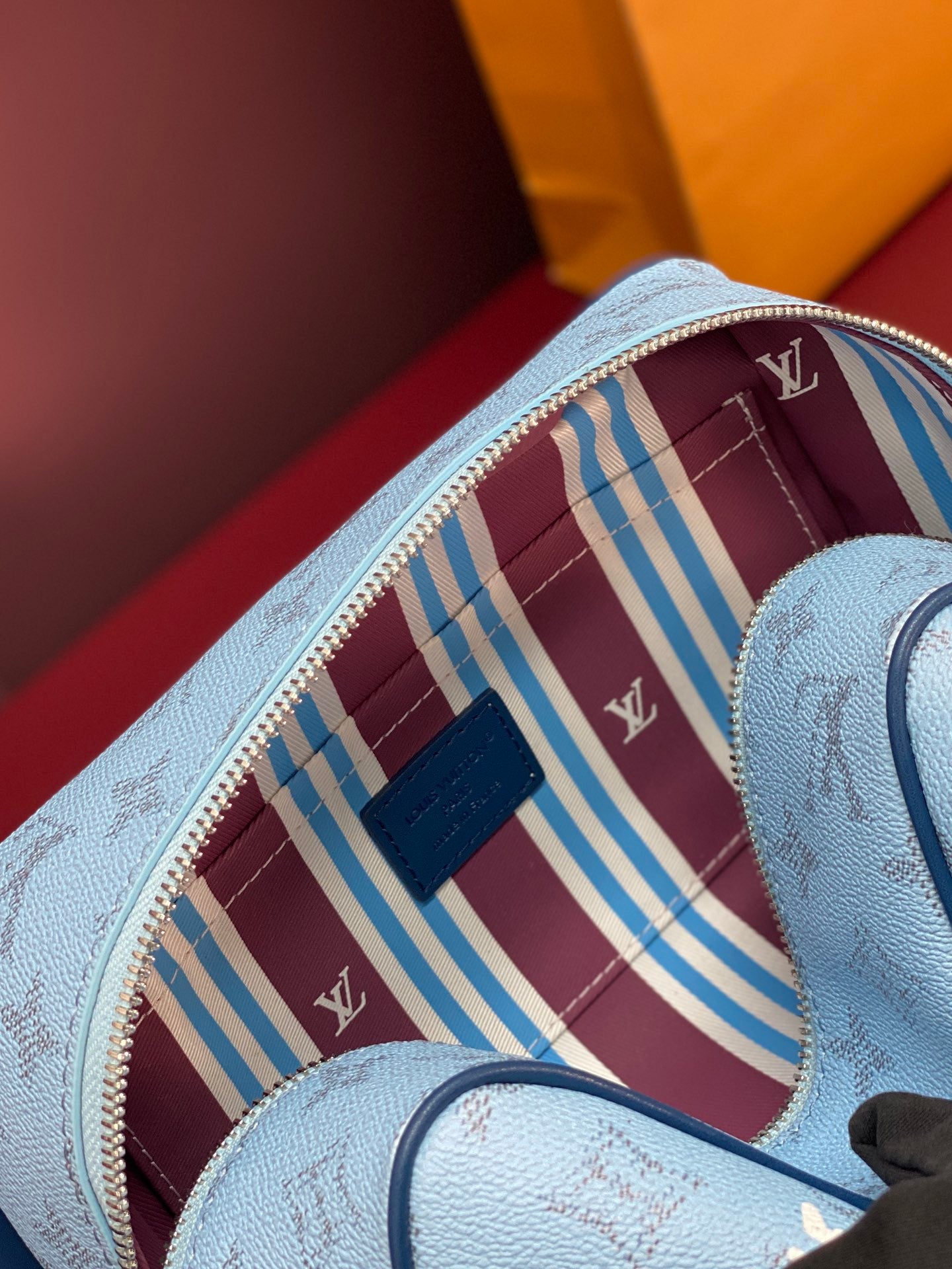 Louis Vuitton light blue monogram bag with open zipper and burgundy striped interior