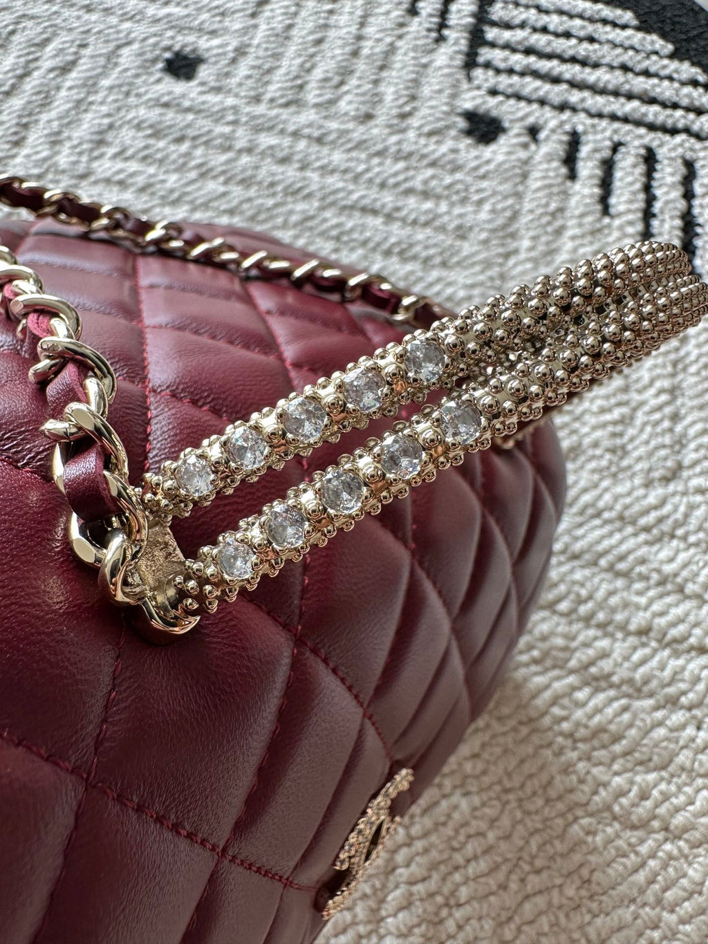 Burgundy quilted bag with rhinestone chain trim and metal chain handle