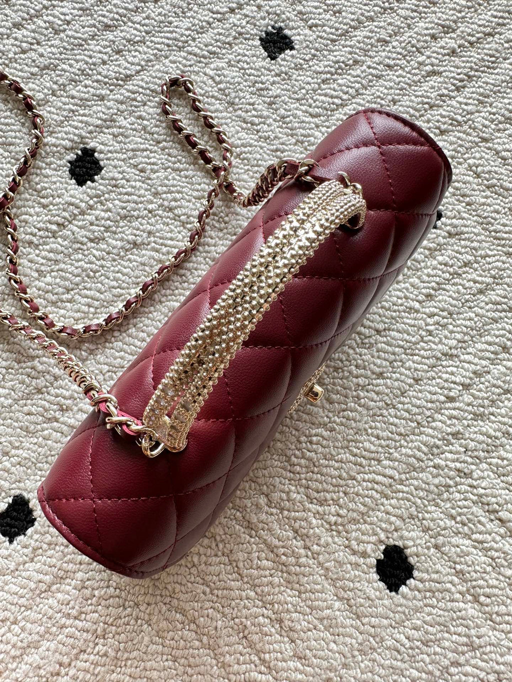 Burgundy quilted shoulder bag with embellished chain strap and round clasp
