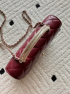 Burgundy quilted shoulder bag with embellished chain strap and round clasp