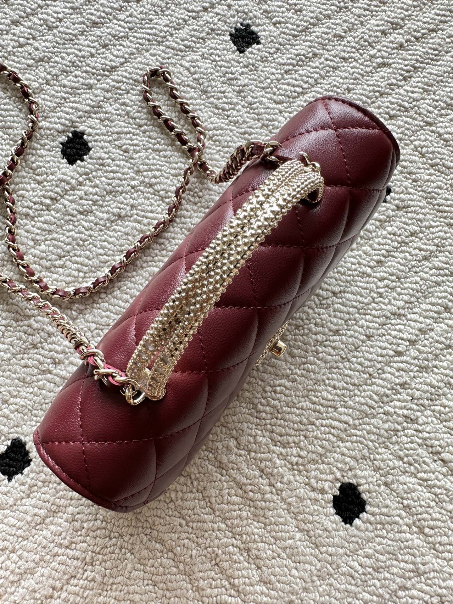 Burgundy quilted shoulder bag with embellished chain strap and round clasp