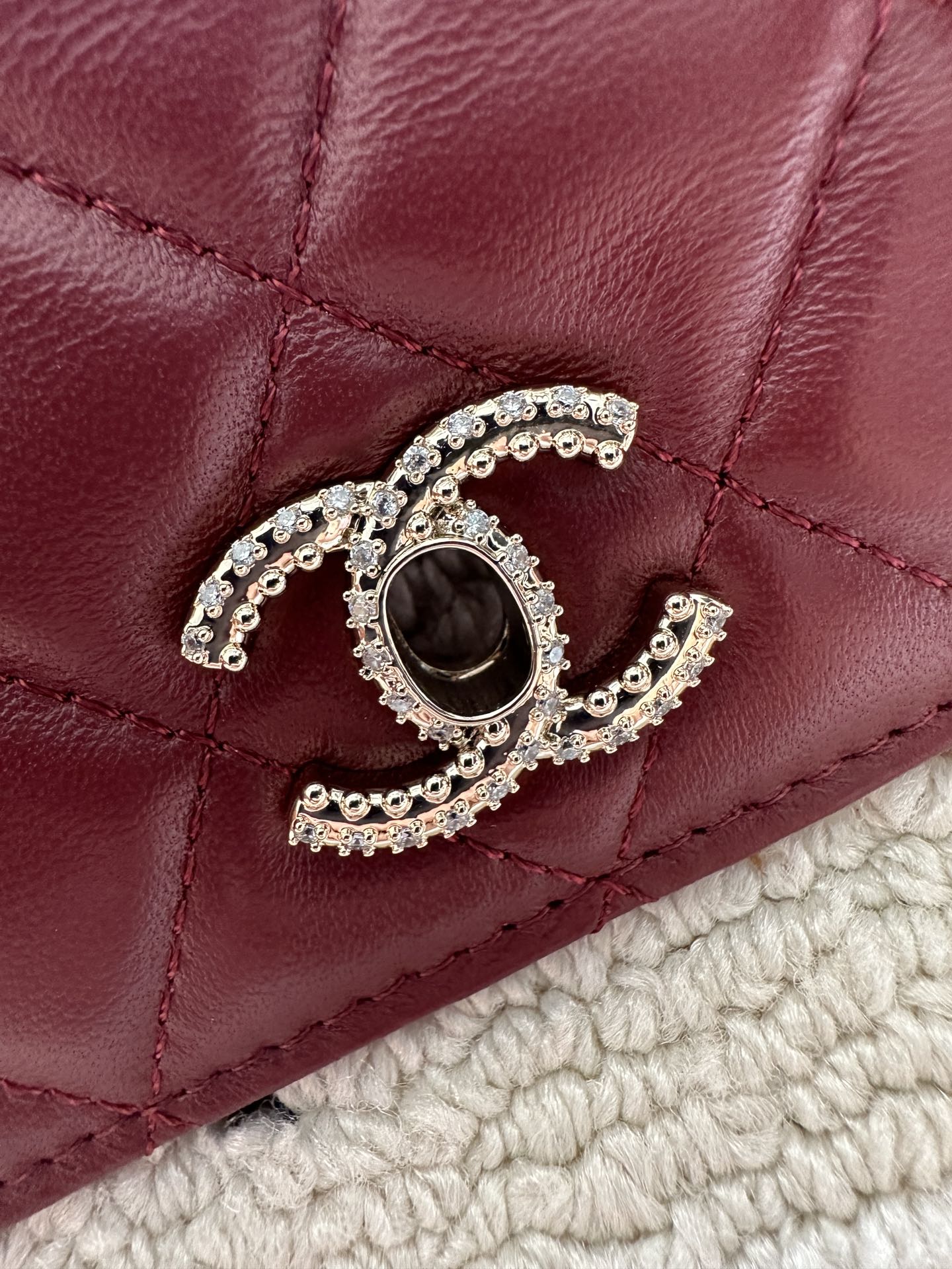 Burgundy quilted flap with Chanel logo and rhinestone button hardware