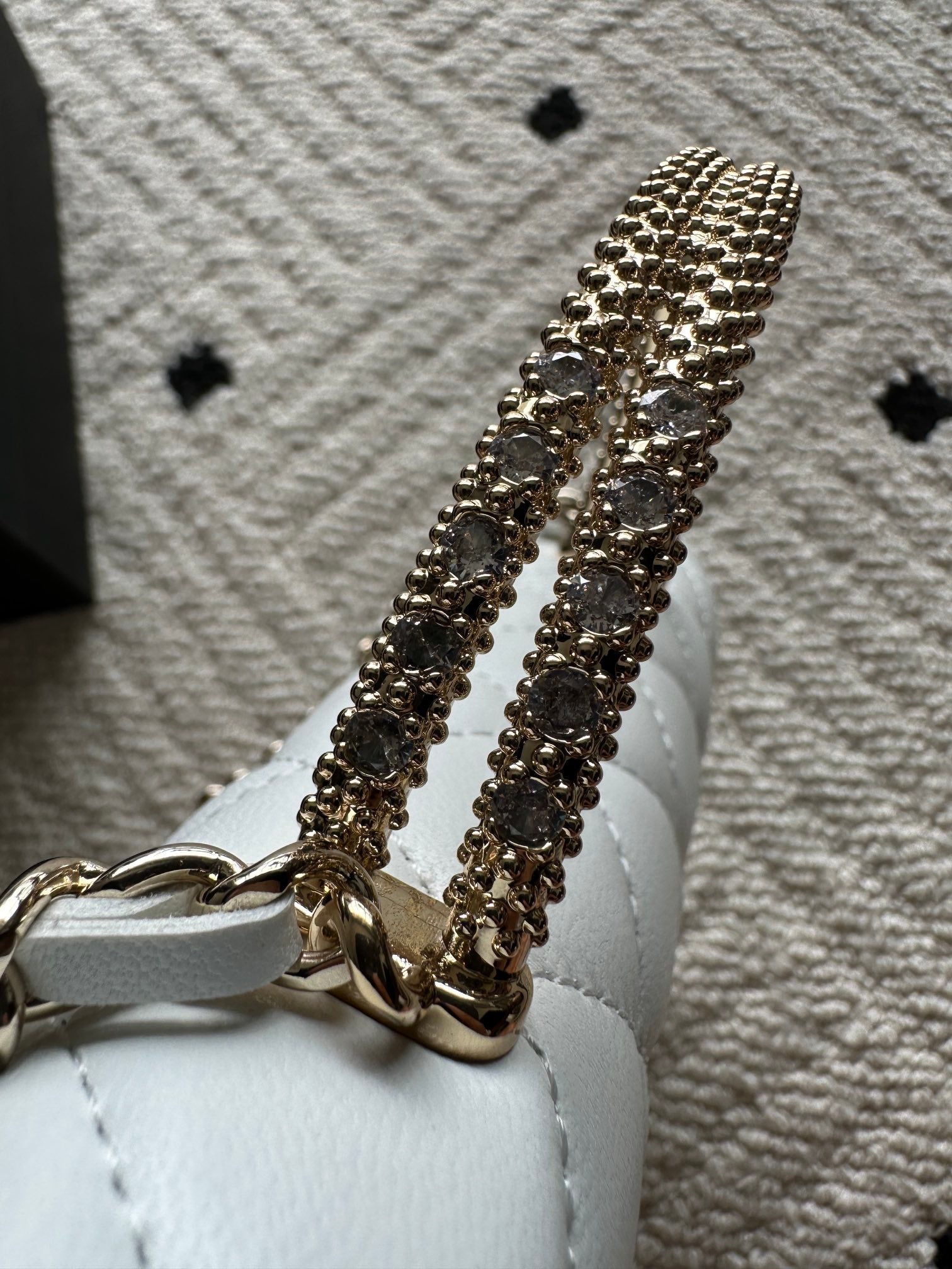 Gold-tone chain strap detail on a white quilted mini flap bag.