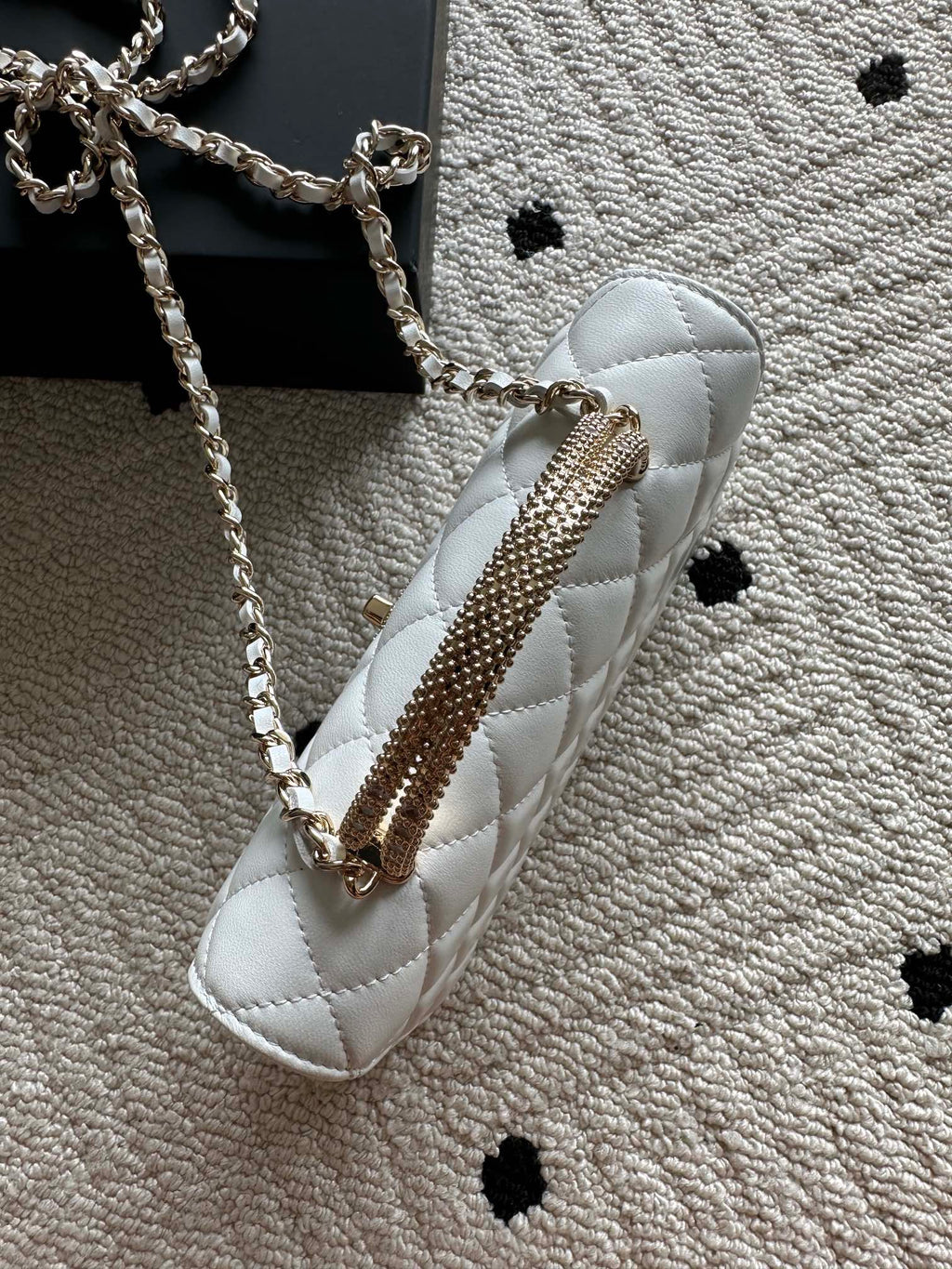 White quilted mini flap bag with long chain strap and top handle.