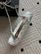 White quilted mini flap bag with long chain strap and top handle.
