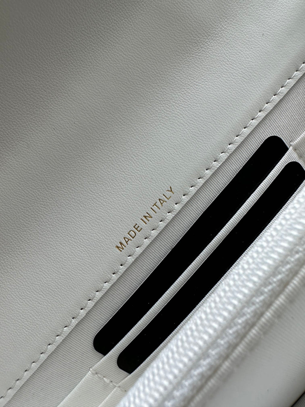 White leather flap bag showing 'MADE IN ITALY' near a card slot.