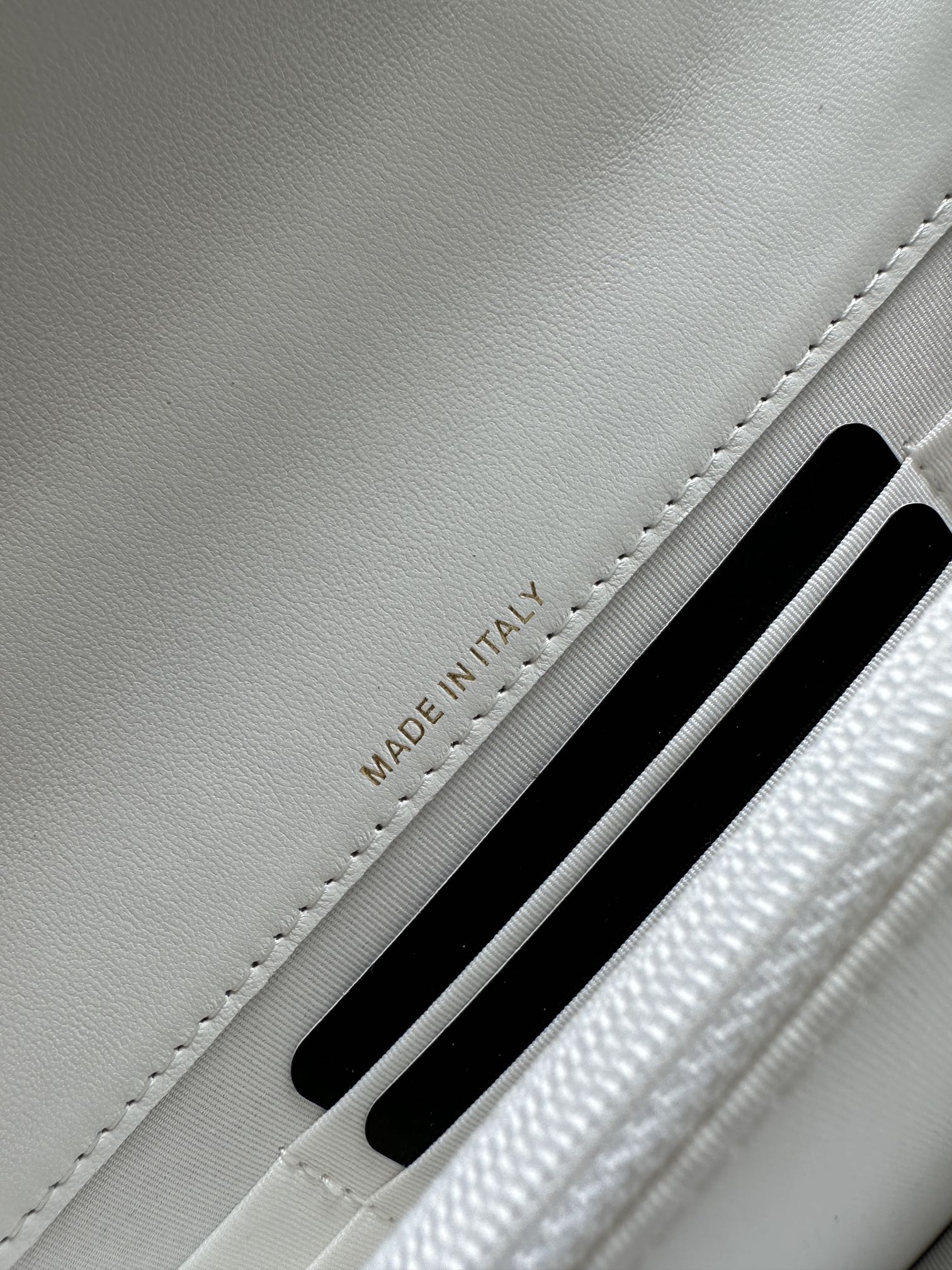 White leather flap bag showing 'MADE IN ITALY' near a card slot.