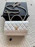 White quilted flap bag with chain strap and gold-tone clasp hardware.