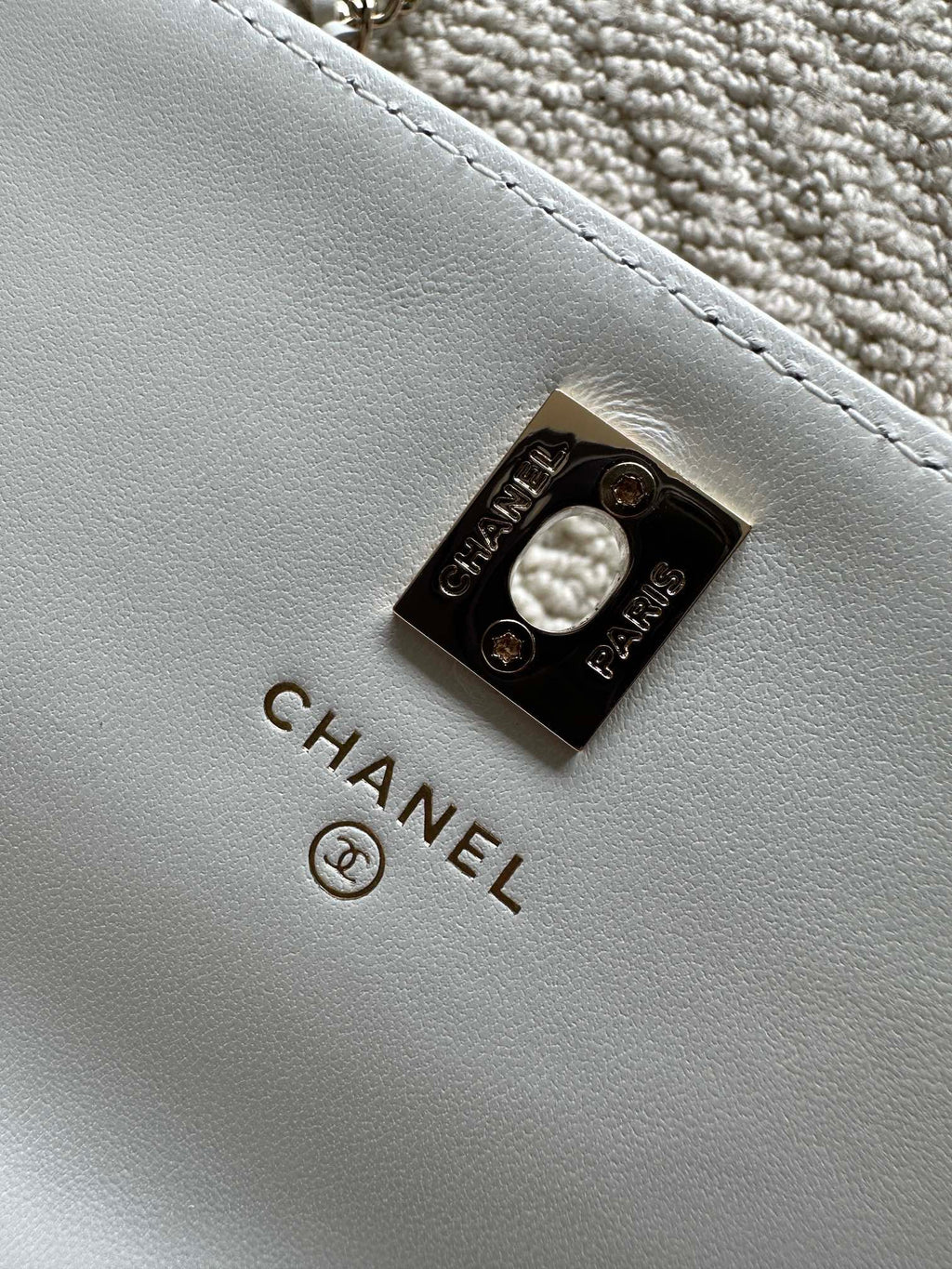 White leather flap bag with CHANEL logo metal turn-lock clasp.