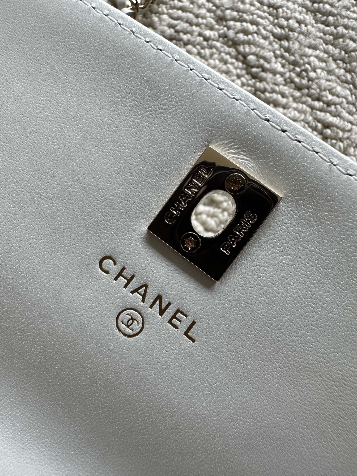 White leather flap bag with CHANEL logo metal turn-lock clasp.