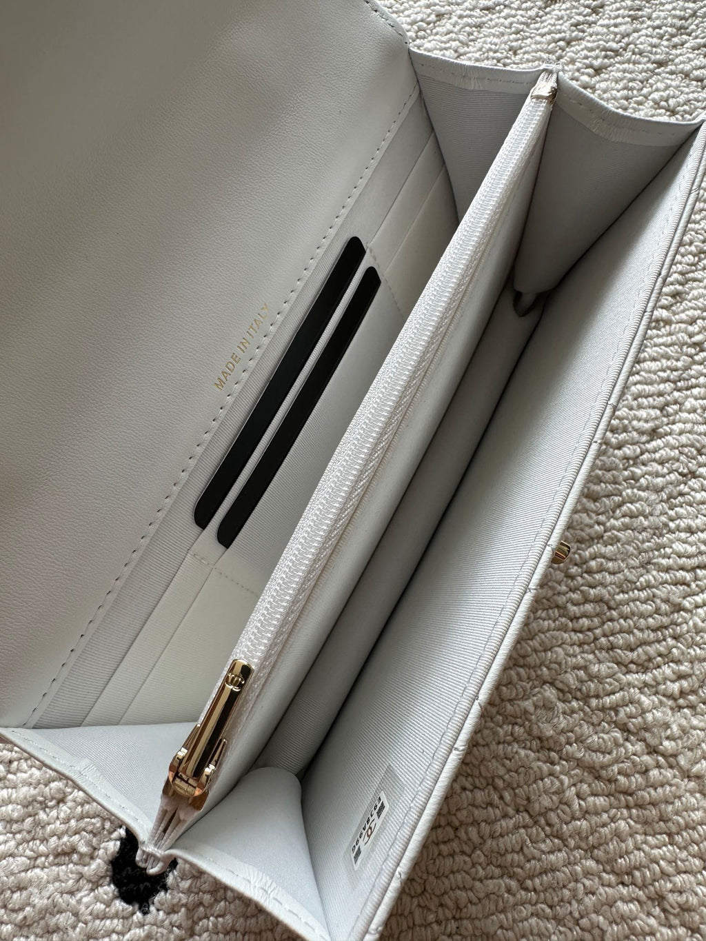 White quilted flap bag interior with card slot and chain hardware.