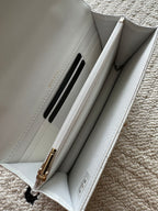 White quilted flap bag interior with card slot and chain hardware.