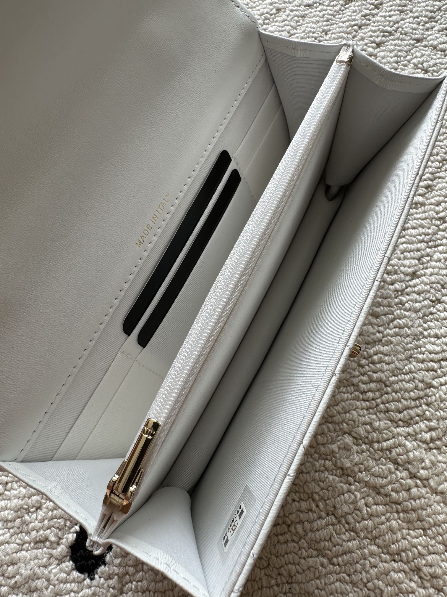 White quilted flap bag interior with card slot and chain hardware.
