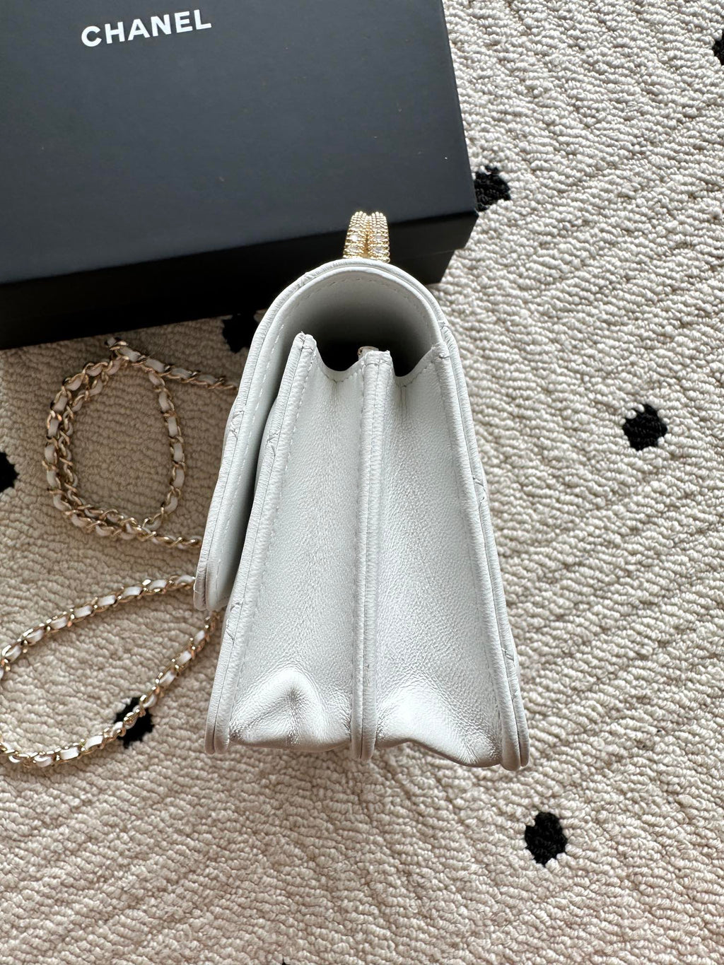 White quilted mini flap bag with open top and drawstring-like flap edges.