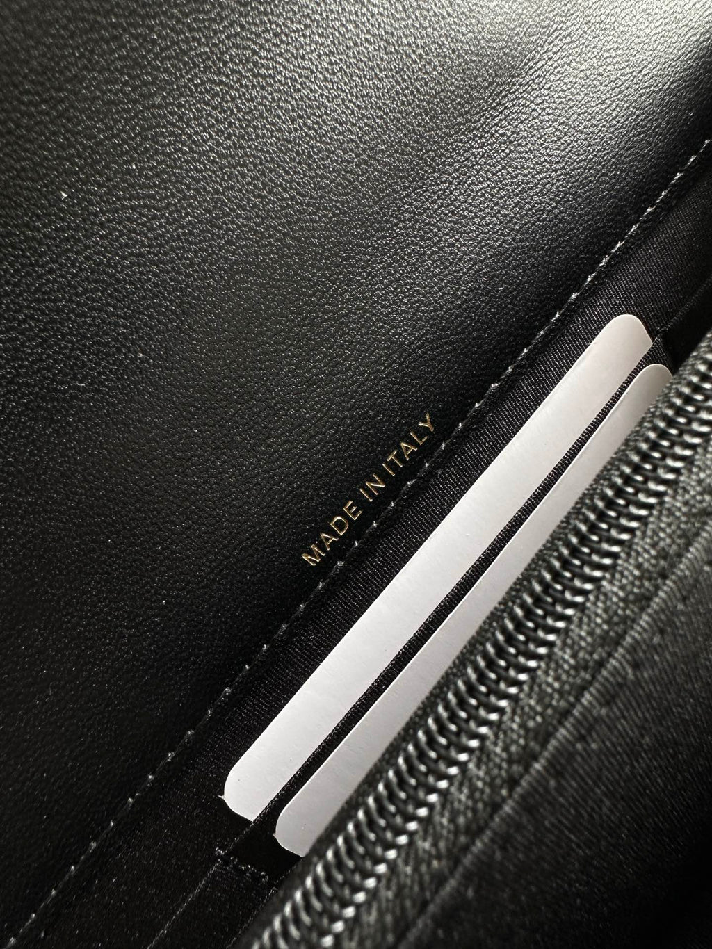 Chanel black bag interior label reading “MADE IN ITALY” near zipper