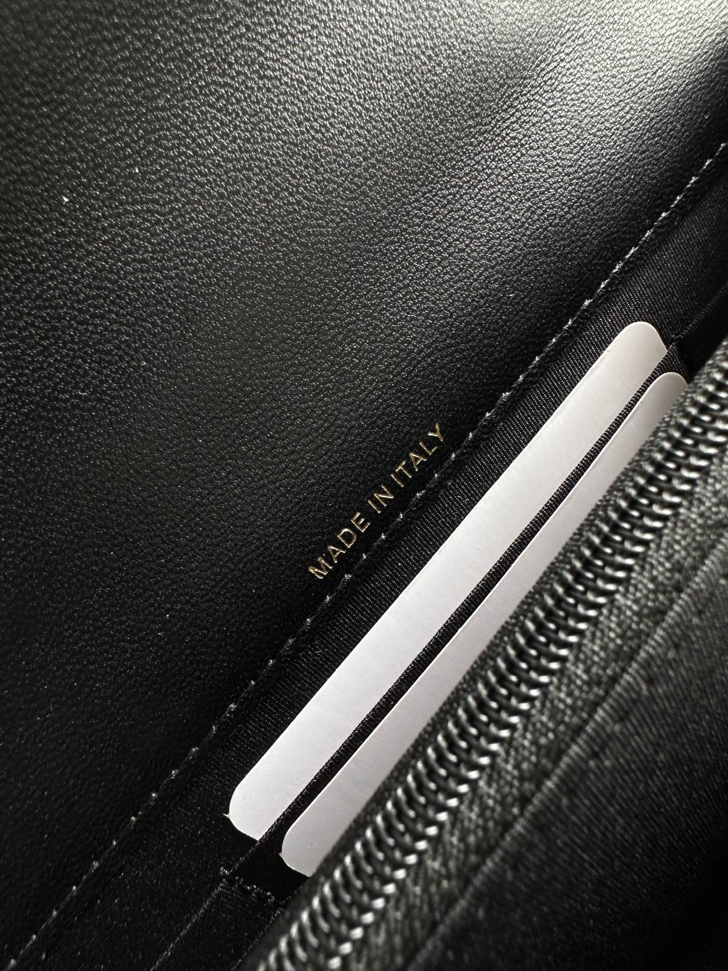 Chanel black bag interior label reading “MADE IN ITALY” near zipper