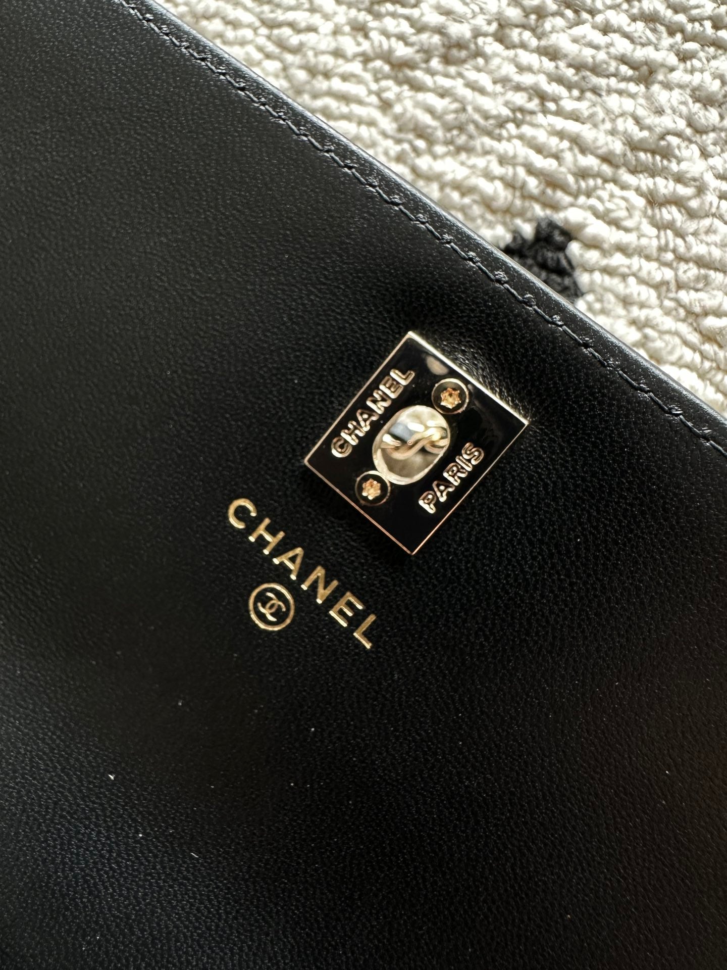 Chanel metal logo plate on black leather mini bag with gold trim