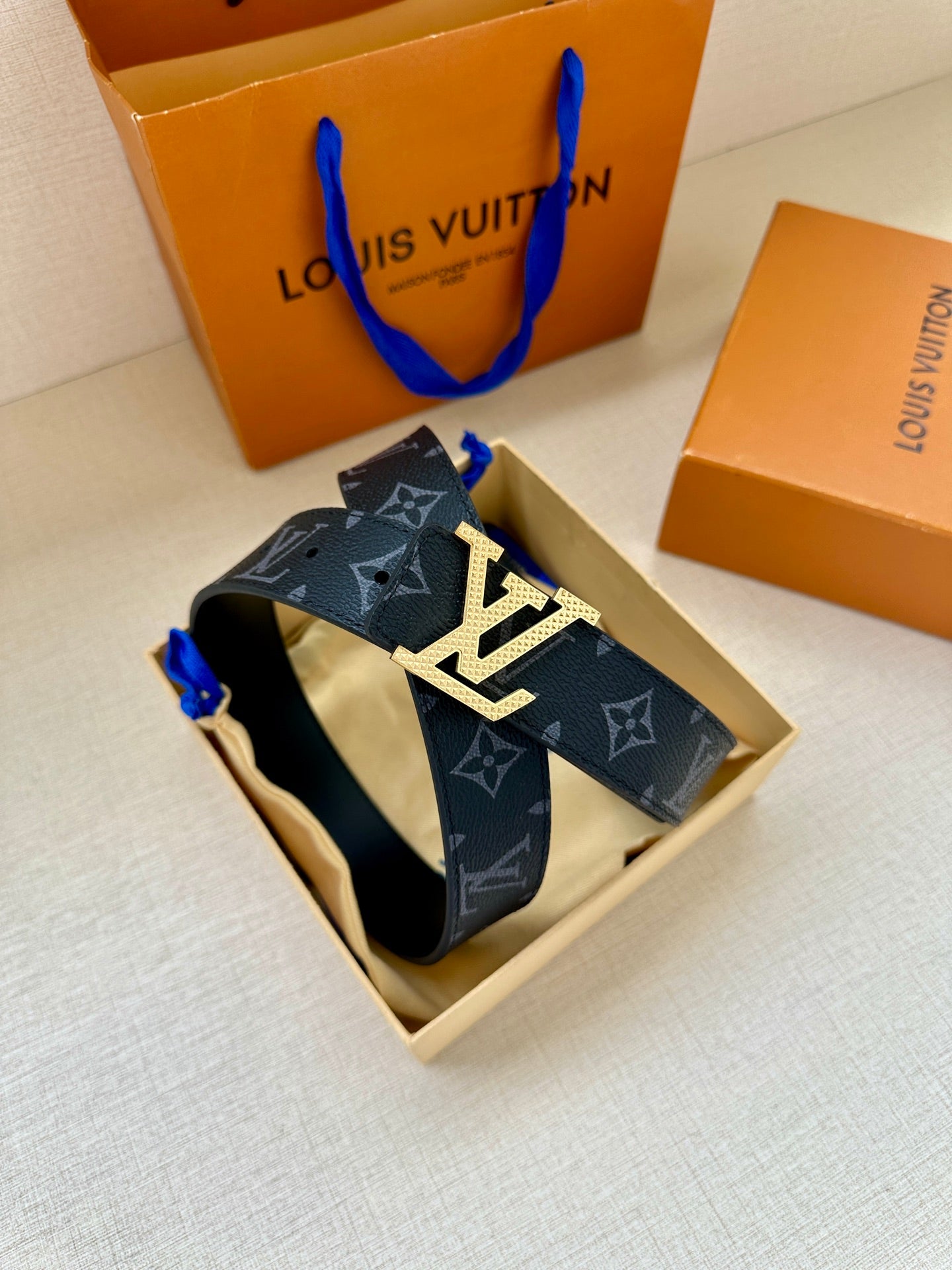 Louis Vuitton belt in box view: dark navy monogram strap with silver LV buckle on top
