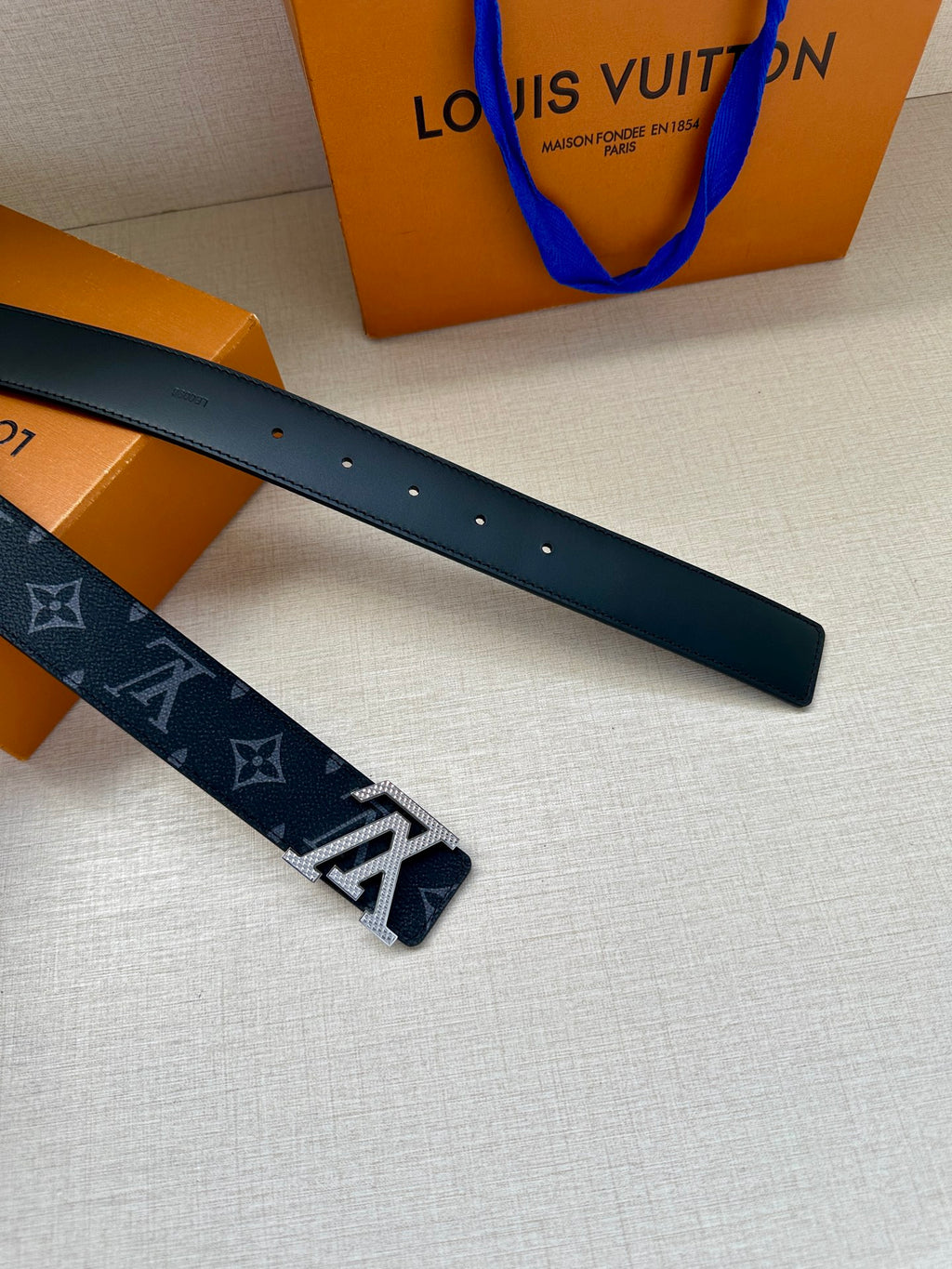 Louis Vuitton belt flat view: dark navy monogram strap with perforated adjustment holes