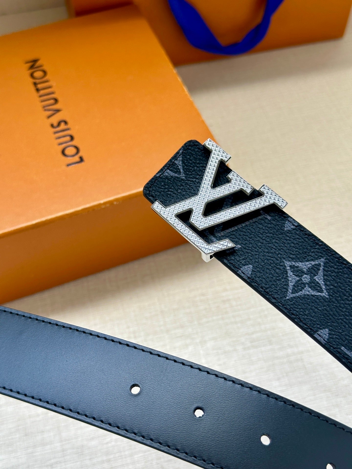 Louis Vuitton belt close-up of silver buckle over dark navy monogram strap and dark holes