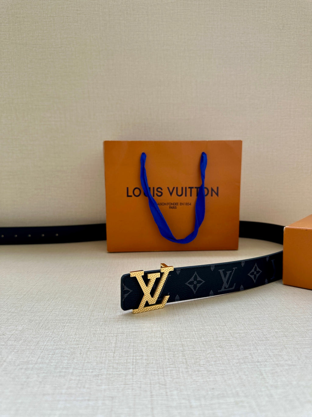 Louis Vuitton belt on display: dark navy monogram strap with silver LV buckle at side