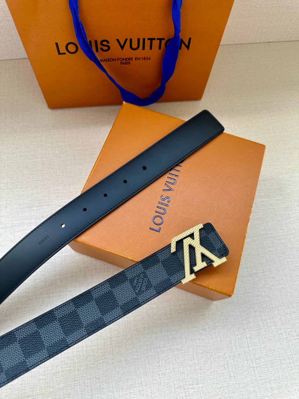 Louis Vuitton checkered leather belt with LV buckle and perforated strap holes.