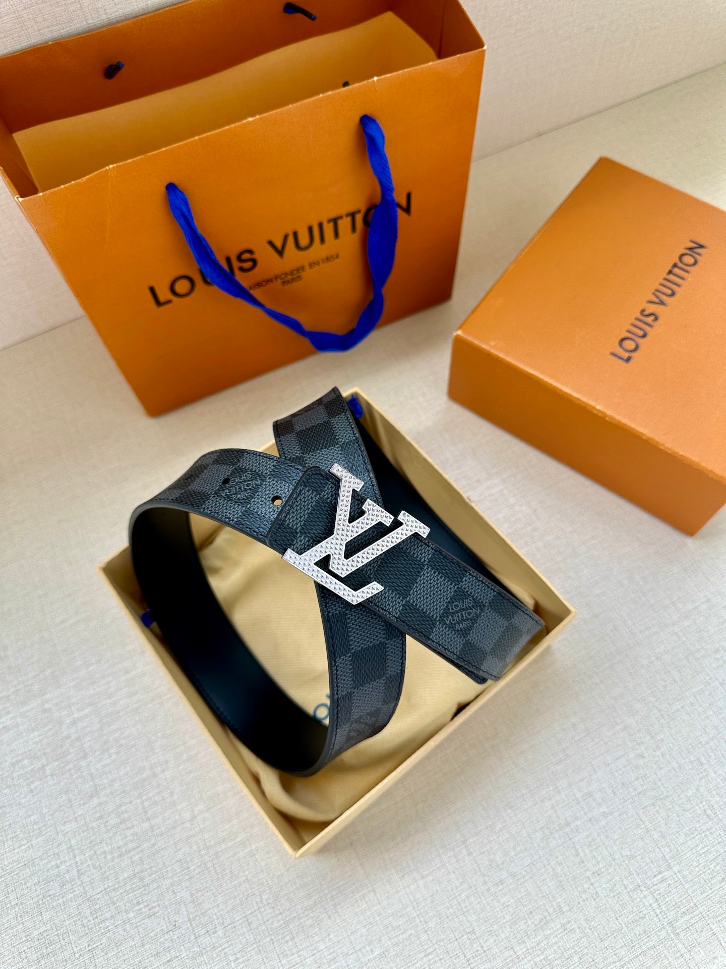 Louis Vuitton checkered leather belt with LV buckle and folded strap loop.