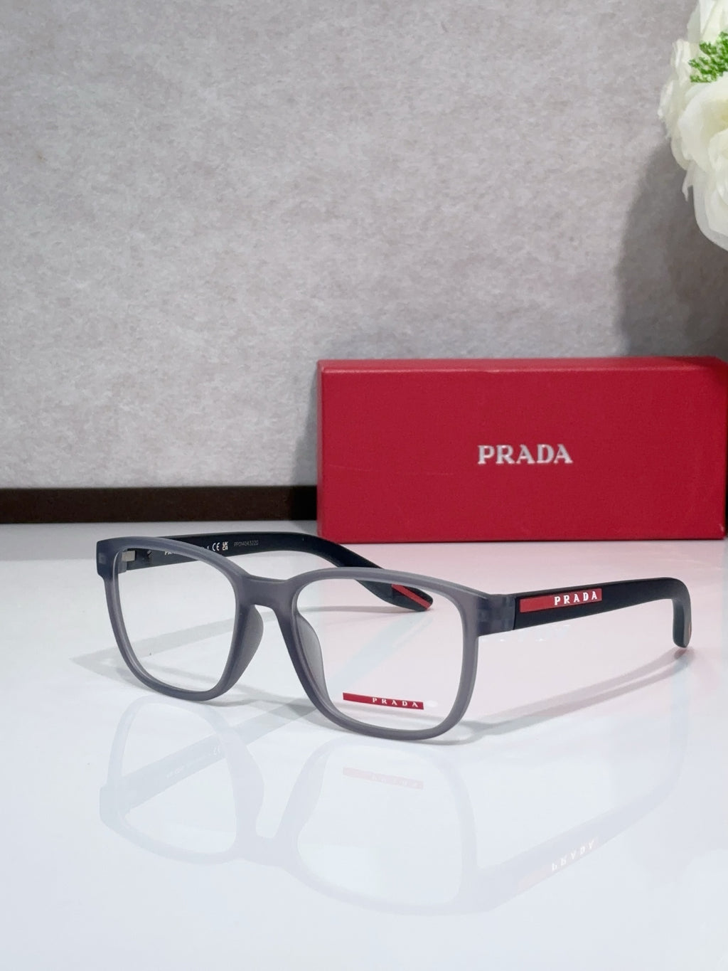 Dark blue-gray eyeglasses with Prada logo on temple, rectangular full-rim frame.