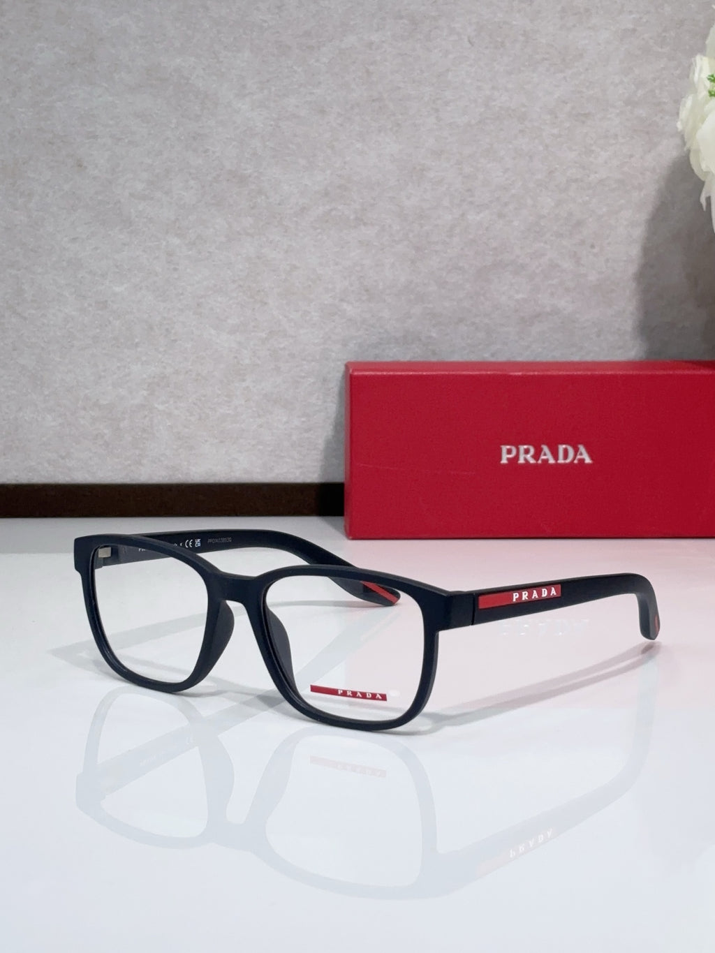 Navy eyeglasses with red Prada logo on temple, rectangular full-rim frame.
