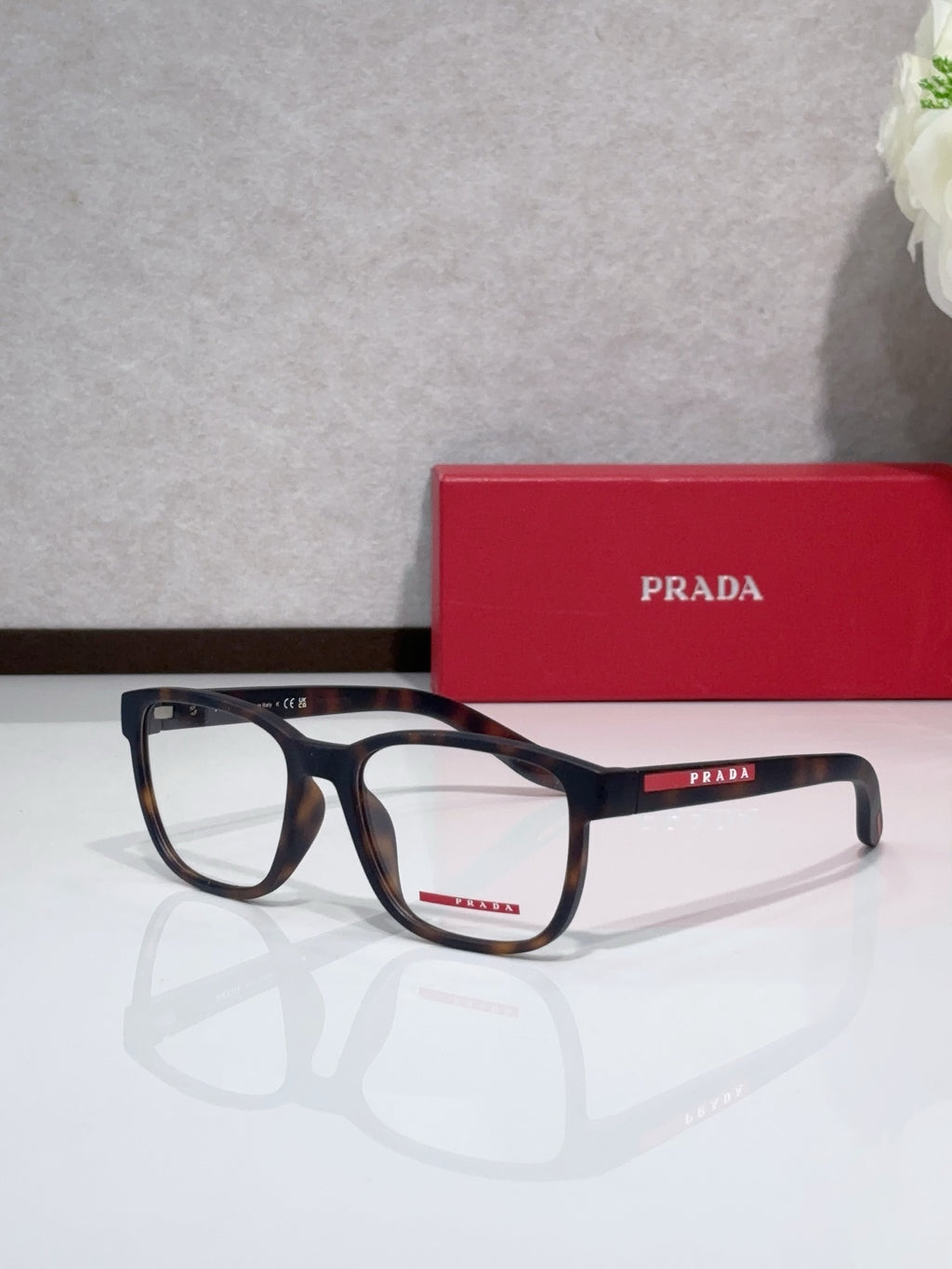 Dark blue eyeglasses with Prada logo on temple, broad rectangular lenses.
