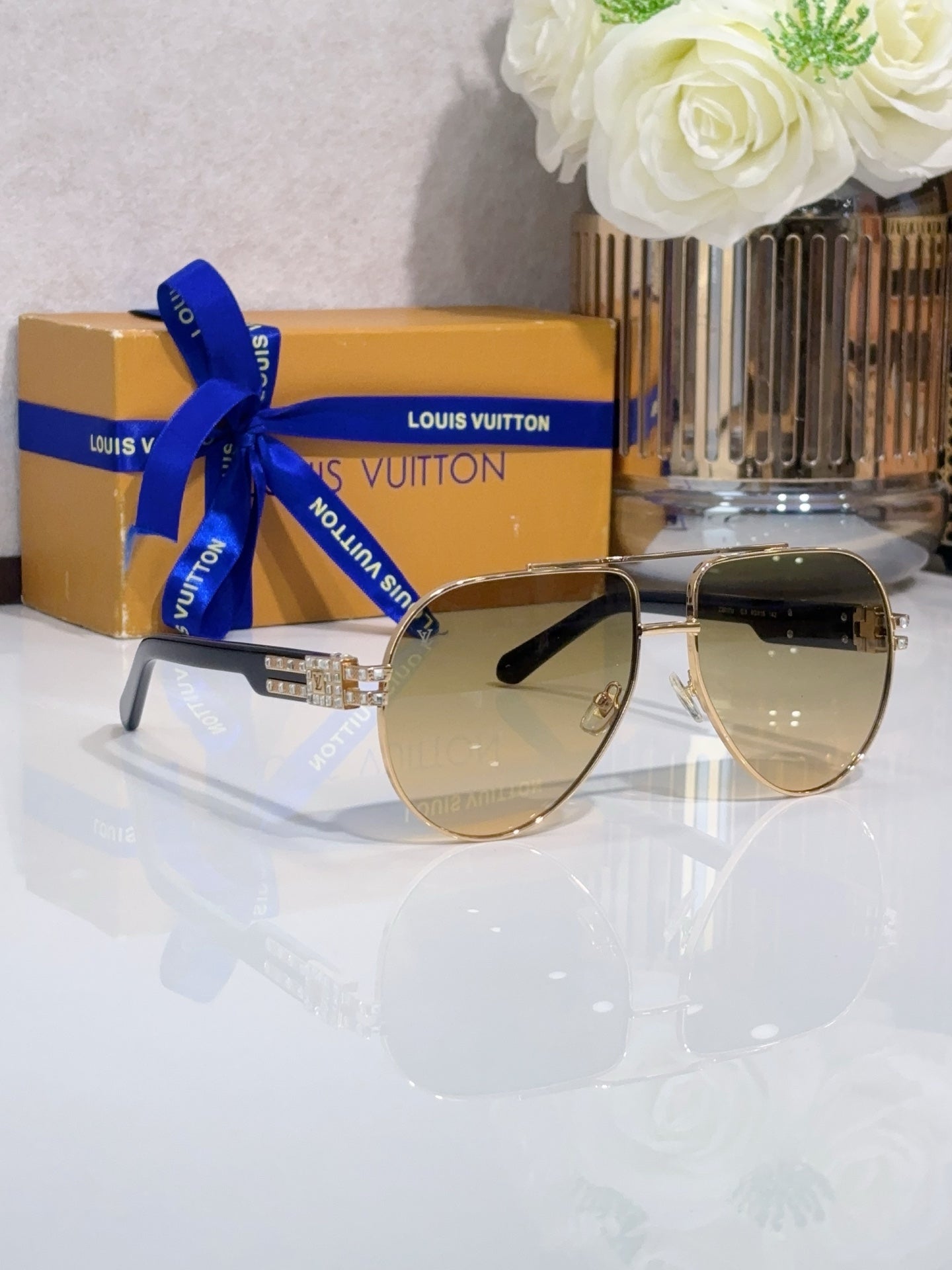 Aviator sunglasses with tinted lenses, gold-tone metal frame, rhinestone detail at temples.