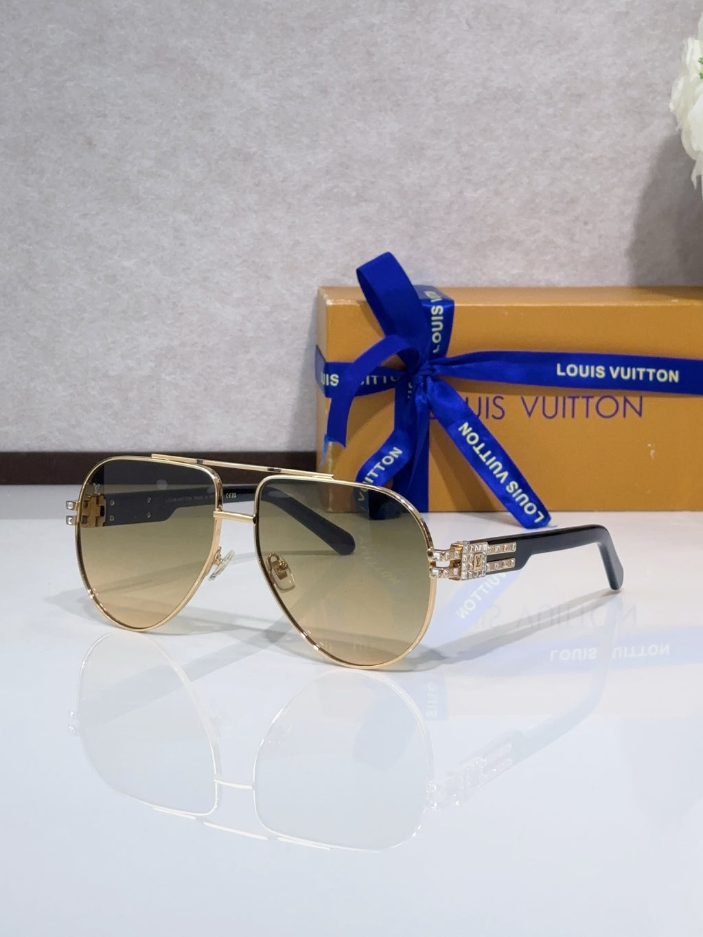 Aviator sunglasses with tinted lenses, gold-tone metal frame, rhinestone detail at temples.