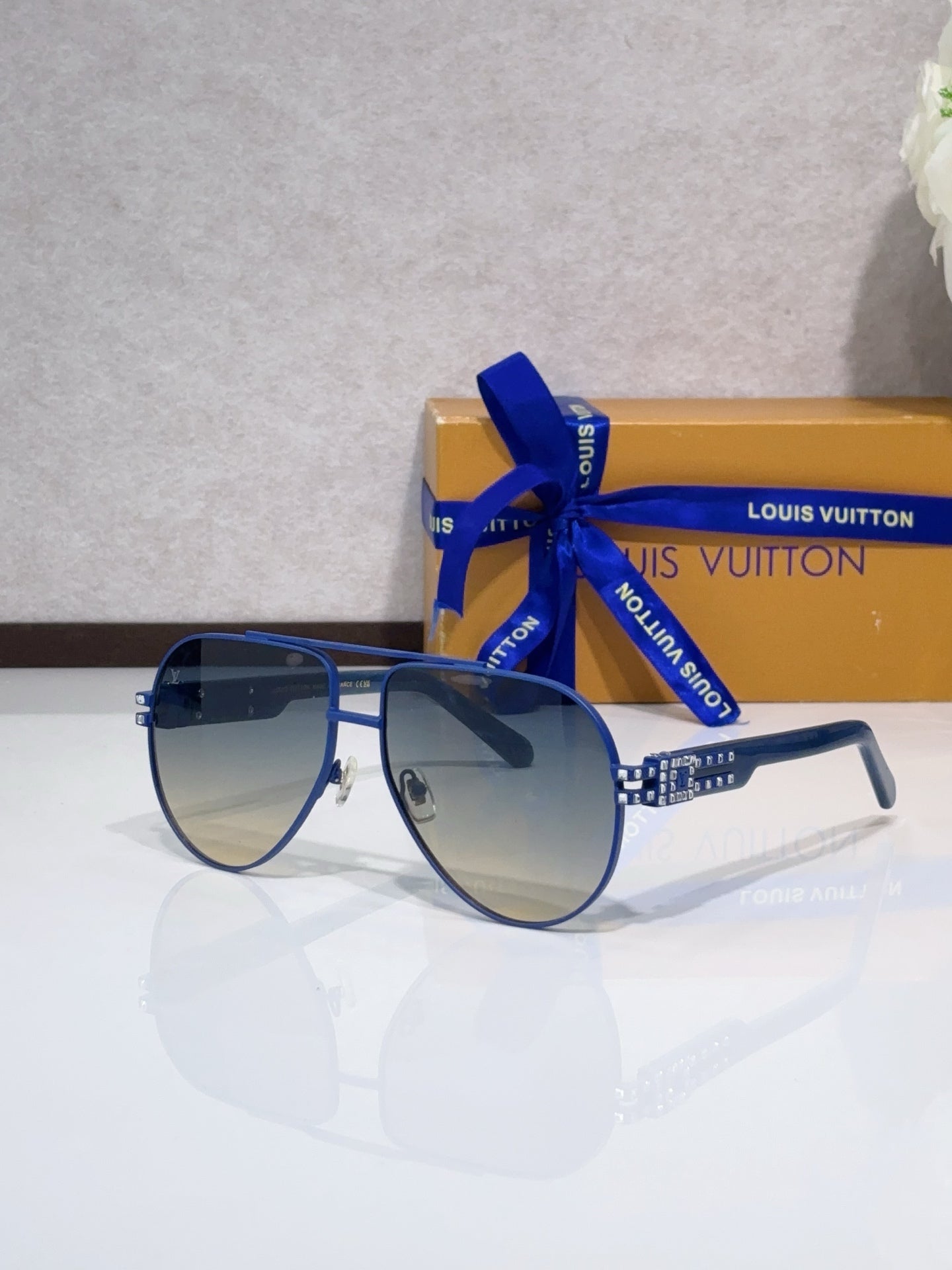Aviator sunglasses with dark lenses, blue metal frame, rhinestone detail at temples.