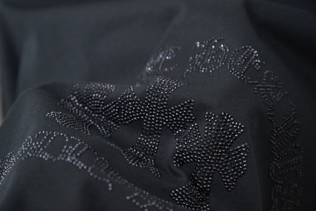 Close-up of rhinestone flower logo on dark T-shirt