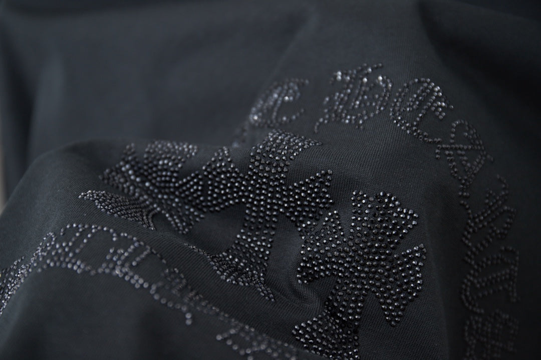 Close-up of rhinestone flower logo on dark T-shirt