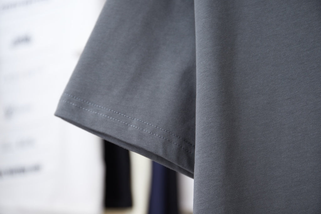 Short-sleeve T-shirt hem detail in dark gray, with neat double stitching