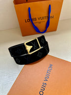 Black monogram belt with gold-tone rectangular buckle, diagonal angle