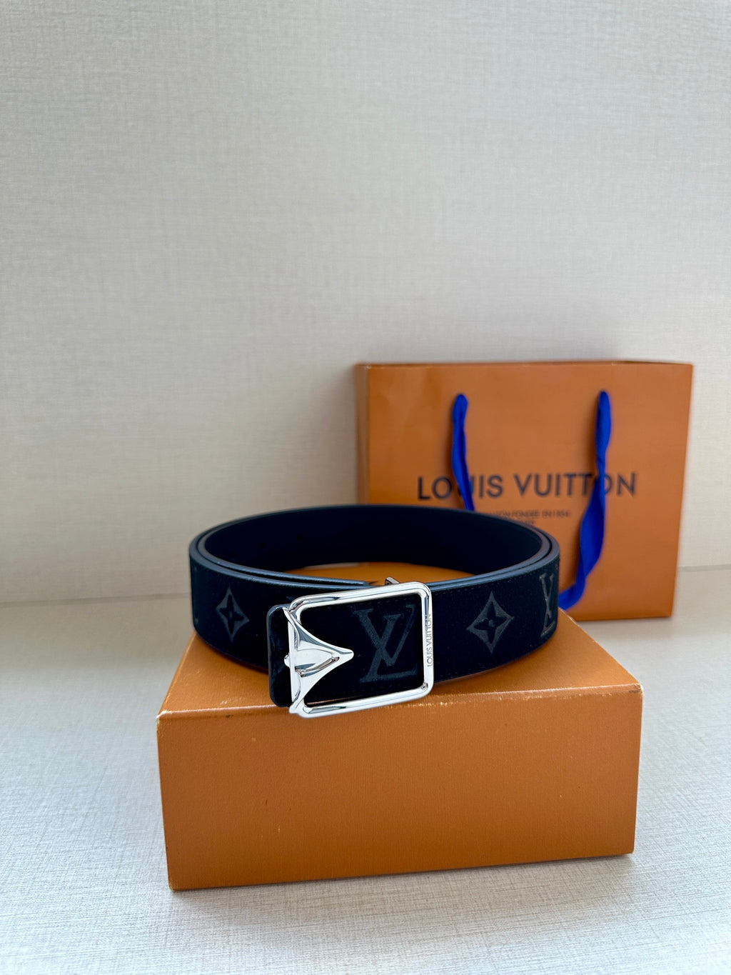 Black monogram belt with silver-tone rectangular buckle, resting pose