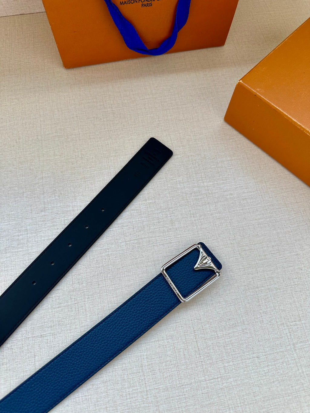 Louis Vuitton belt laid flat with blue strap and silver-tone rectangular buckle