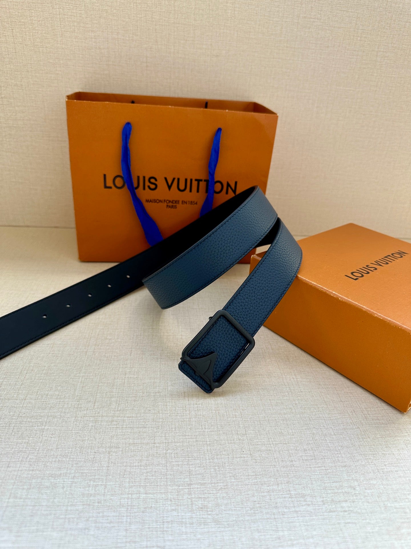 Louis Vuitton belt with blue leather strap and square buckle, shown at an angle