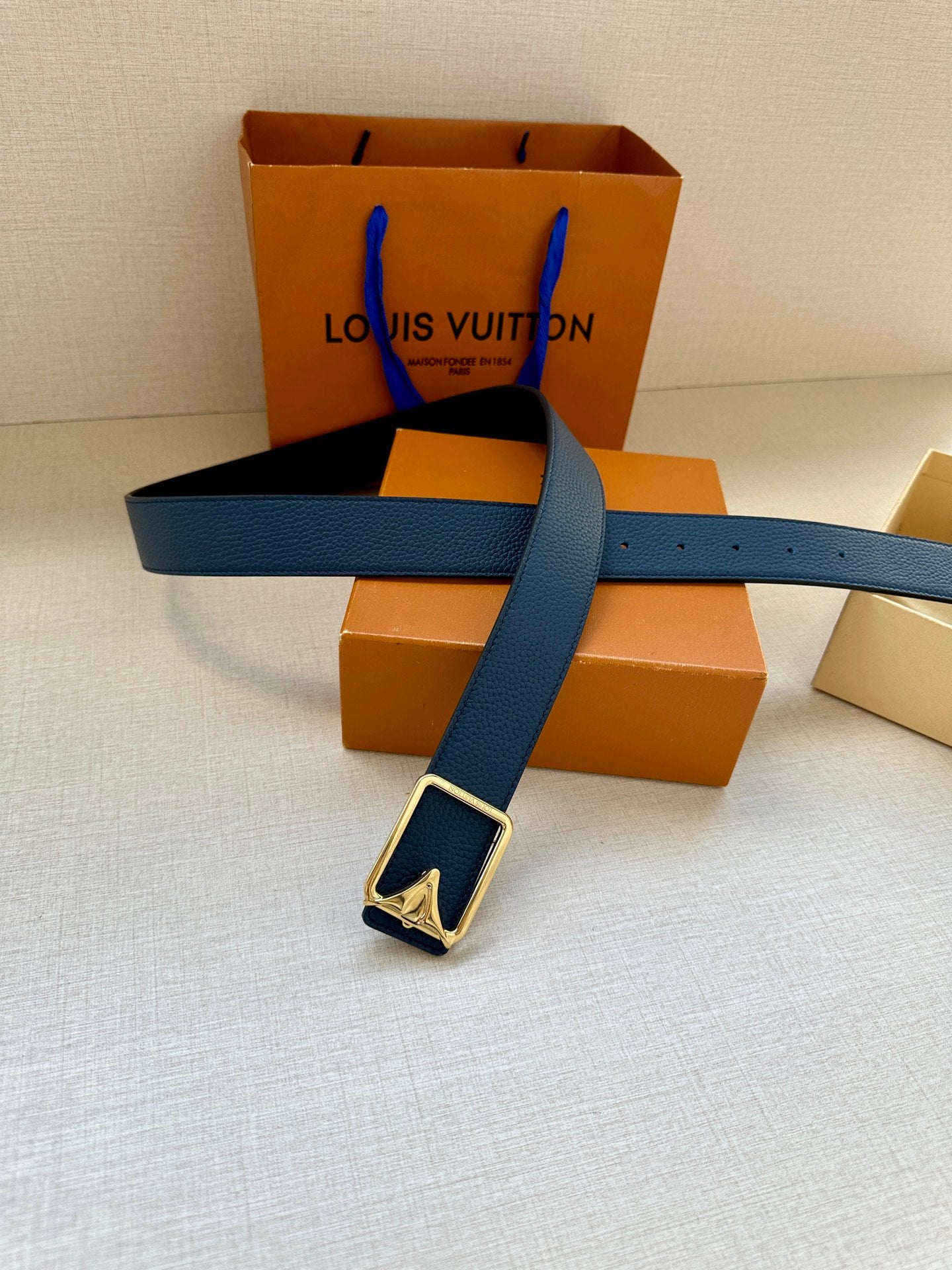 Louis Vuitton belt with blue strap and silver buckle across the belt length