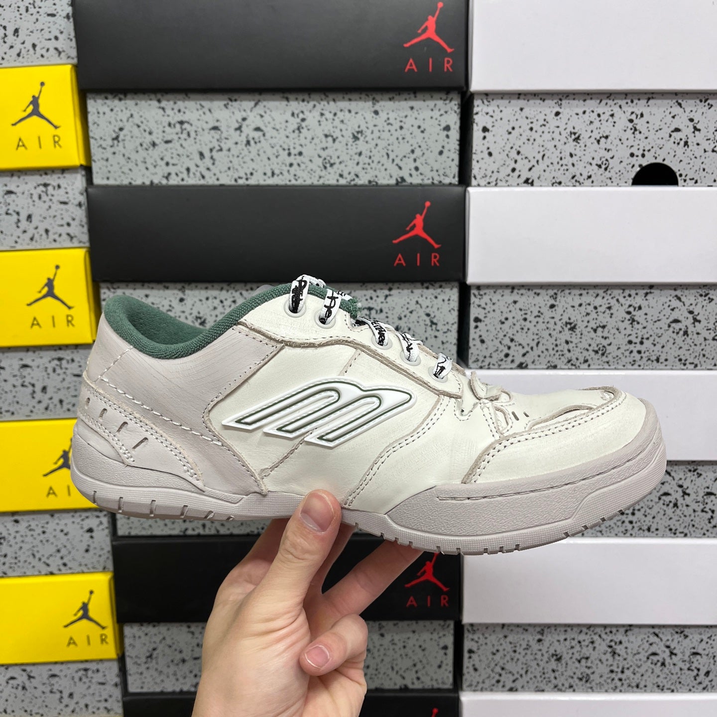 White Balenciaga low-top sneakers with green collar, side logo, and lace-up closure.